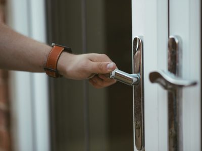 A closeup shot of a person holding a door knob and opening the door