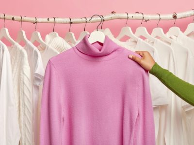 purple-casual-jumper-hangers-womans-hand-against-rail-with-snow-white-clothing_273609-32782